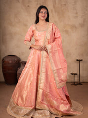 Front view of a model in a blush pink raw silk Anarkali with gold motifs, a wide gold hem and a matching bordered dupatta over one shoulder