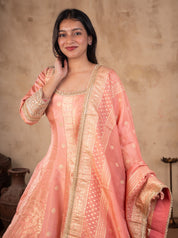 Half-length view of a blush pink raw silk Anarkali with an embellished neckline, gold motifs and a bordered dupatta