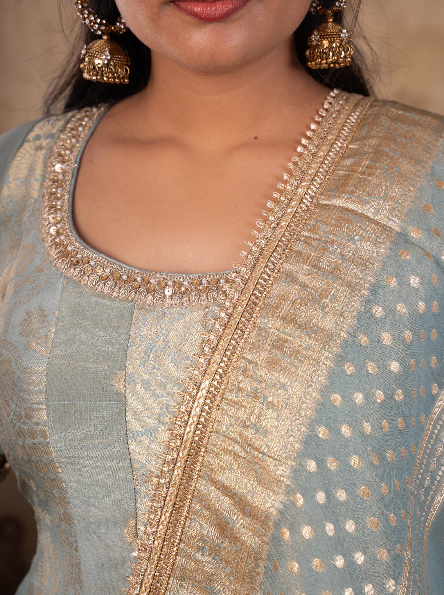 Close-up of the embellished scoop neckline on a pale blue raw silk Anarkali with a wide gold dupatta border