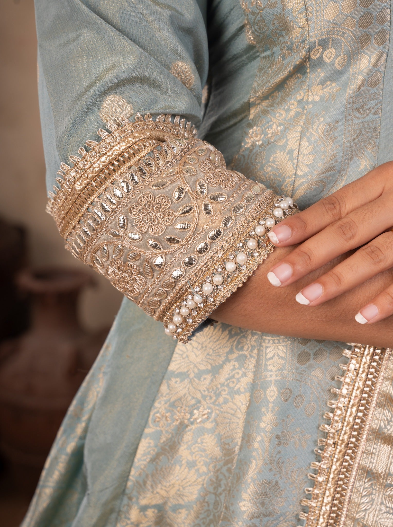 Detail of the embellished cuff and gold motifs on the pale blue raw silk Anarkali sleeve