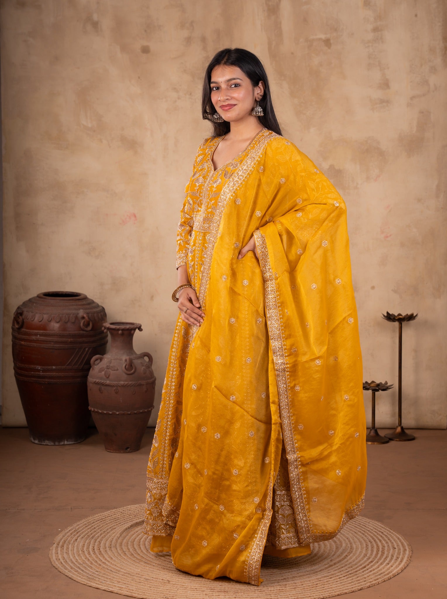Model in a mustard tissue Anarkali with the embroidered dupatta draped over one shoulder