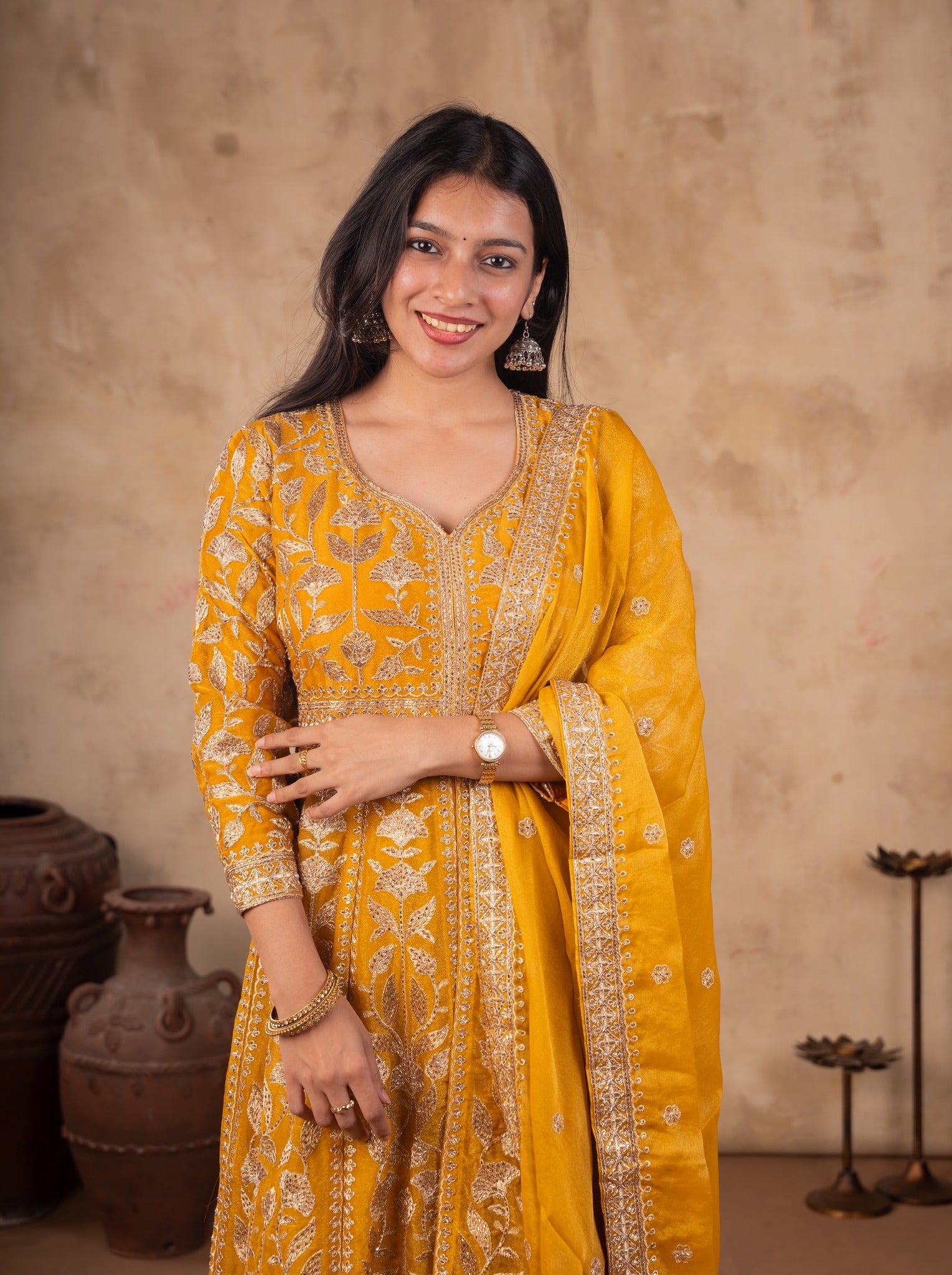 Half-length view of a mustard tissue Anarkali with a V-neckline, floral embroidery and bordered dupatta