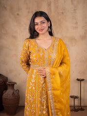 Model smiling in a mustard tissue Anarkali suit with an embroidered V-neck yoke and matching dupatta