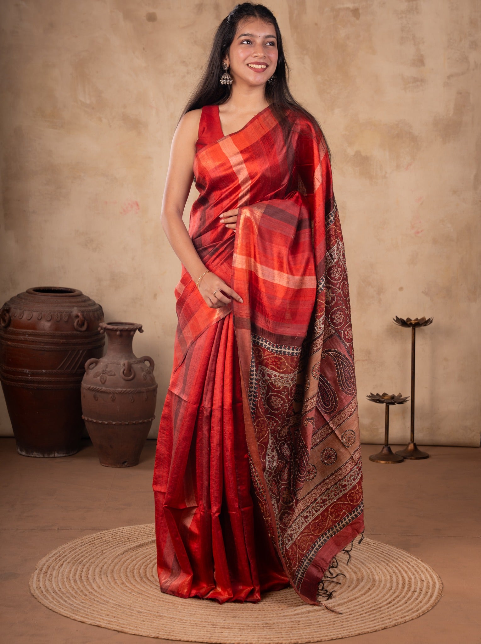 Front view of a model in a maroon tussar silk saree with red and orange checks and a paisley-patterned pallu