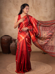 Model holding out the ornate paisley pallu of a maroon checked tussar silk saree
