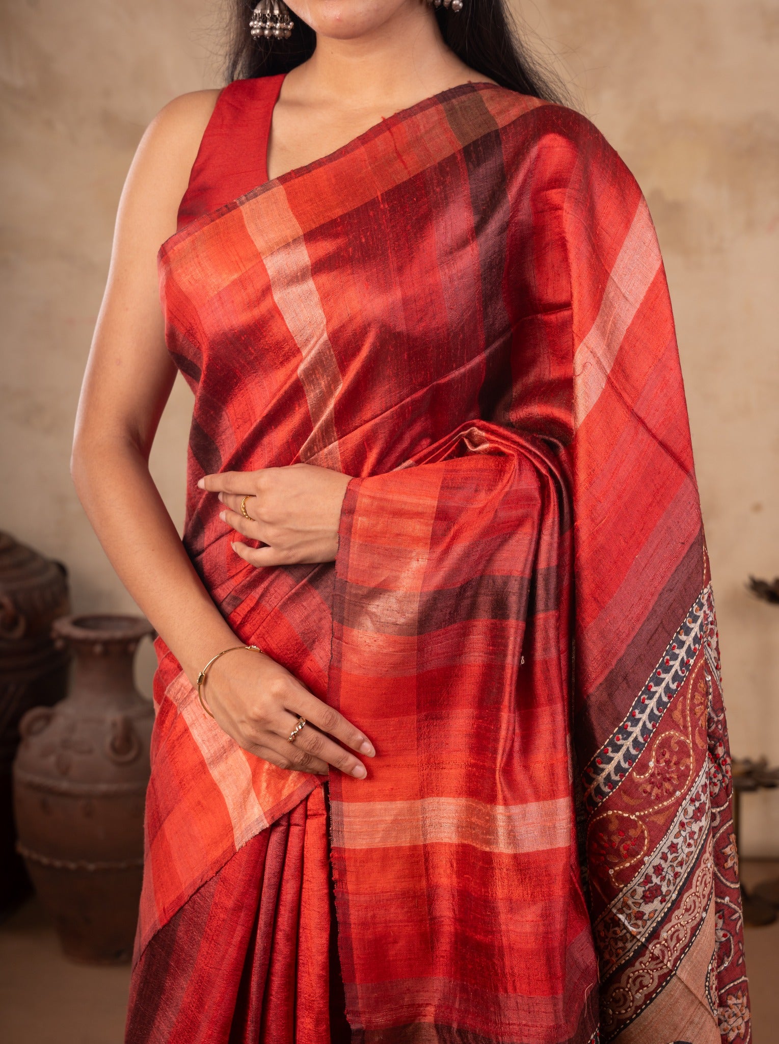 Close-up of the red and orange checks on a maroon tussar silk saree draped over the shoulder