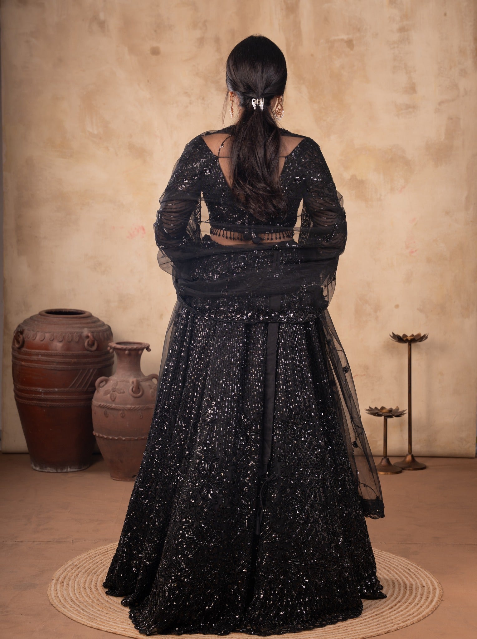 Back view of a black sequinned net lehenga with the sheer dupatta draped behind