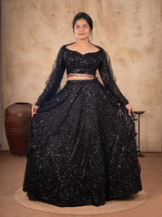 Model holding out the flared skirt of a black sequinned net lehenga with a long-sleeved blouse