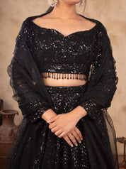 Close-up of the sequinned sweetheart-neck blouse with beaded fringe on a black net lehenga