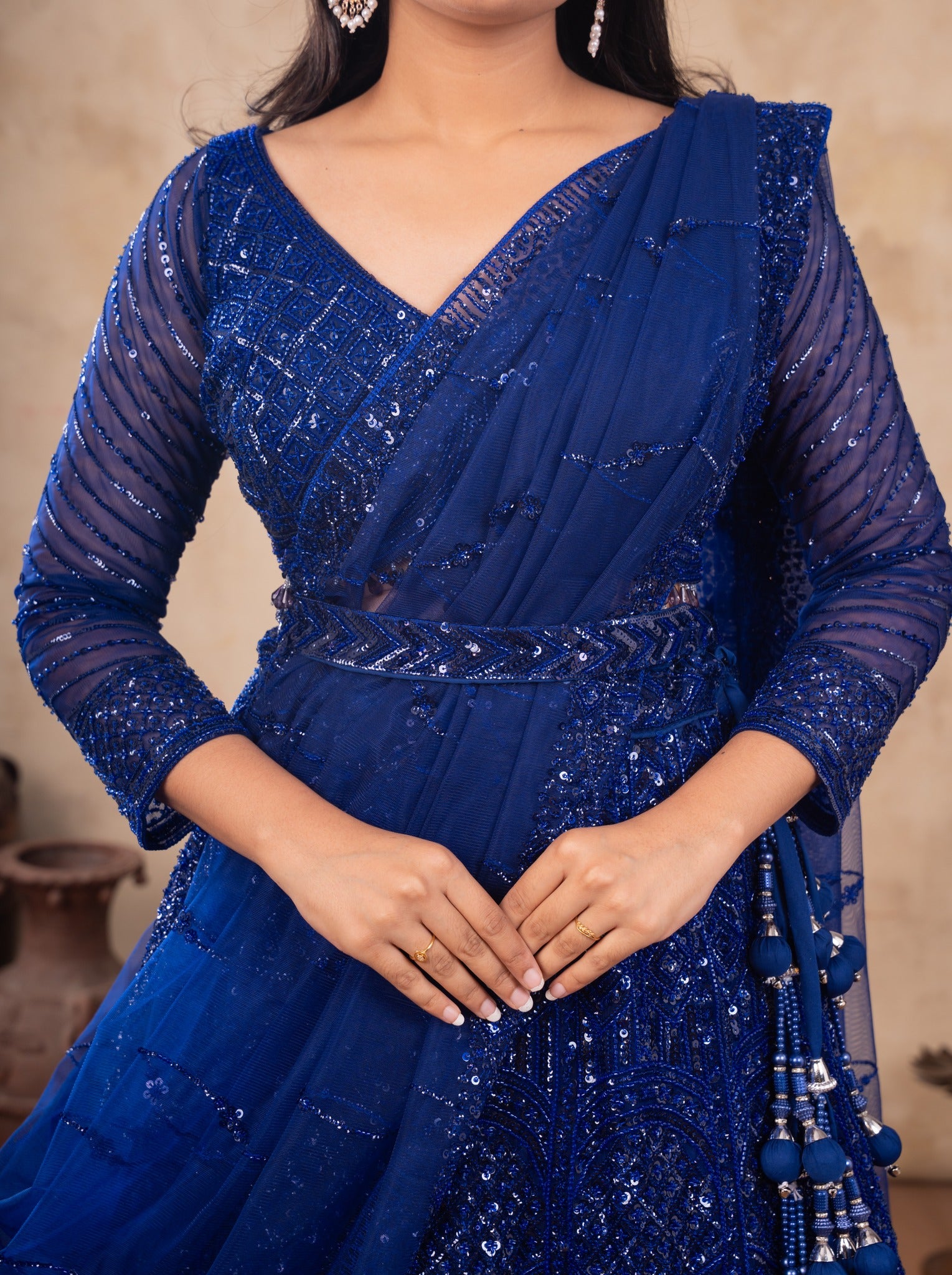 Close-up of a royal blue sequinned net lehenga with a draped dupatta, belted waist and sheer sleeves