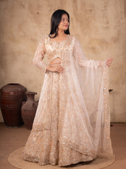 Front view of a model in a cream net lehenga with floral sequin embellishments, sheer sleeves and an embroidered dupatta