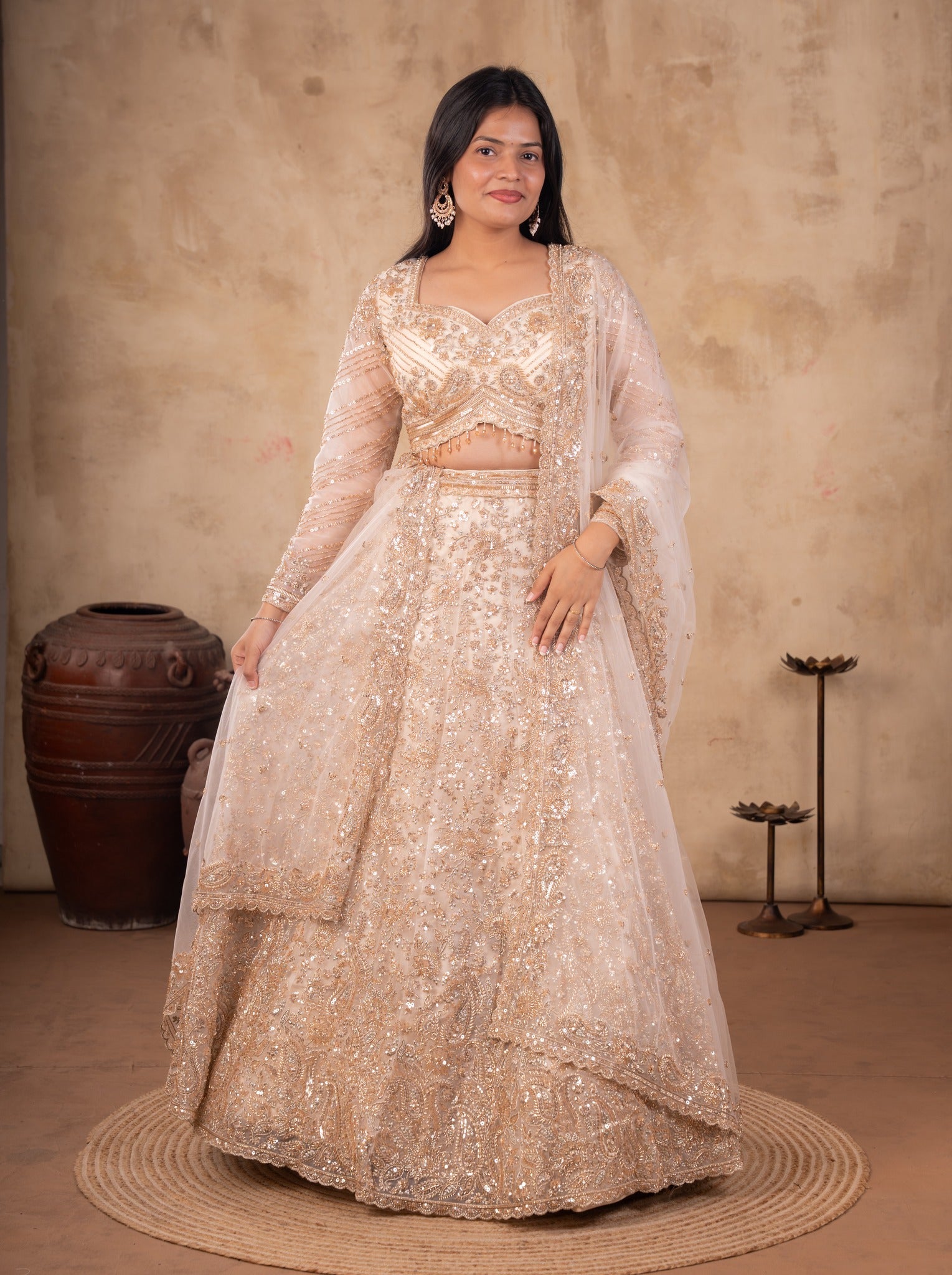Full-length view of a cream net lehenga with a sheer dupatta draped over the shoulder and an embroidered border