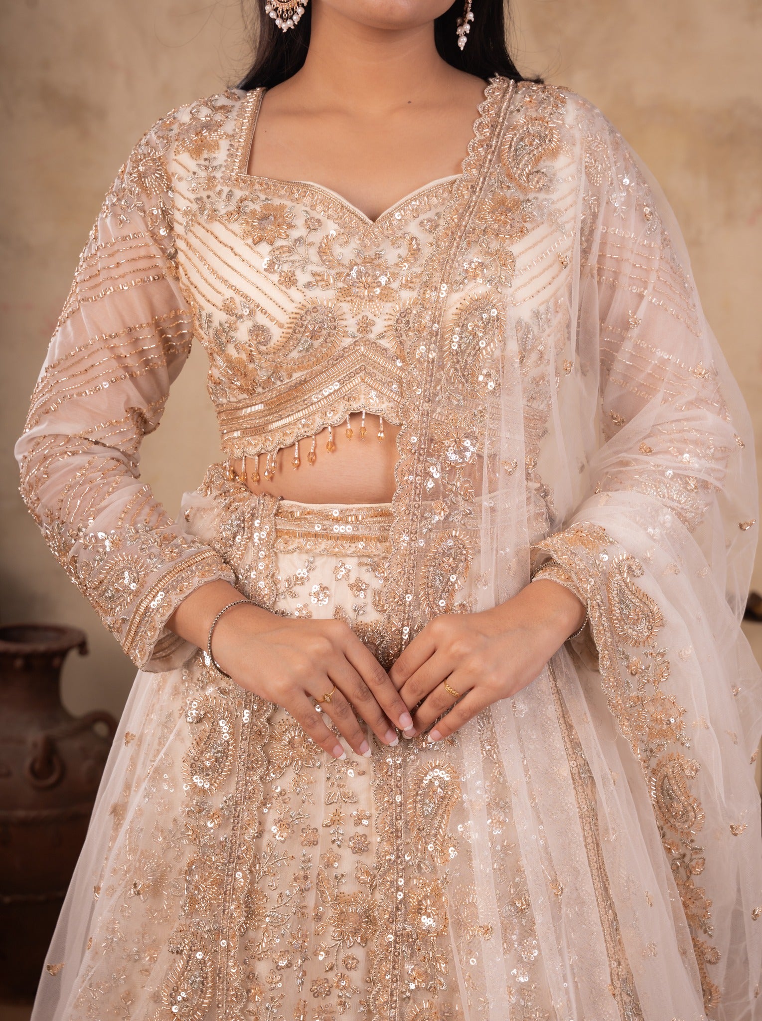 Close-up of the embellished sweetheart-neck blouse and sequinned skirt of a cream net lehenga