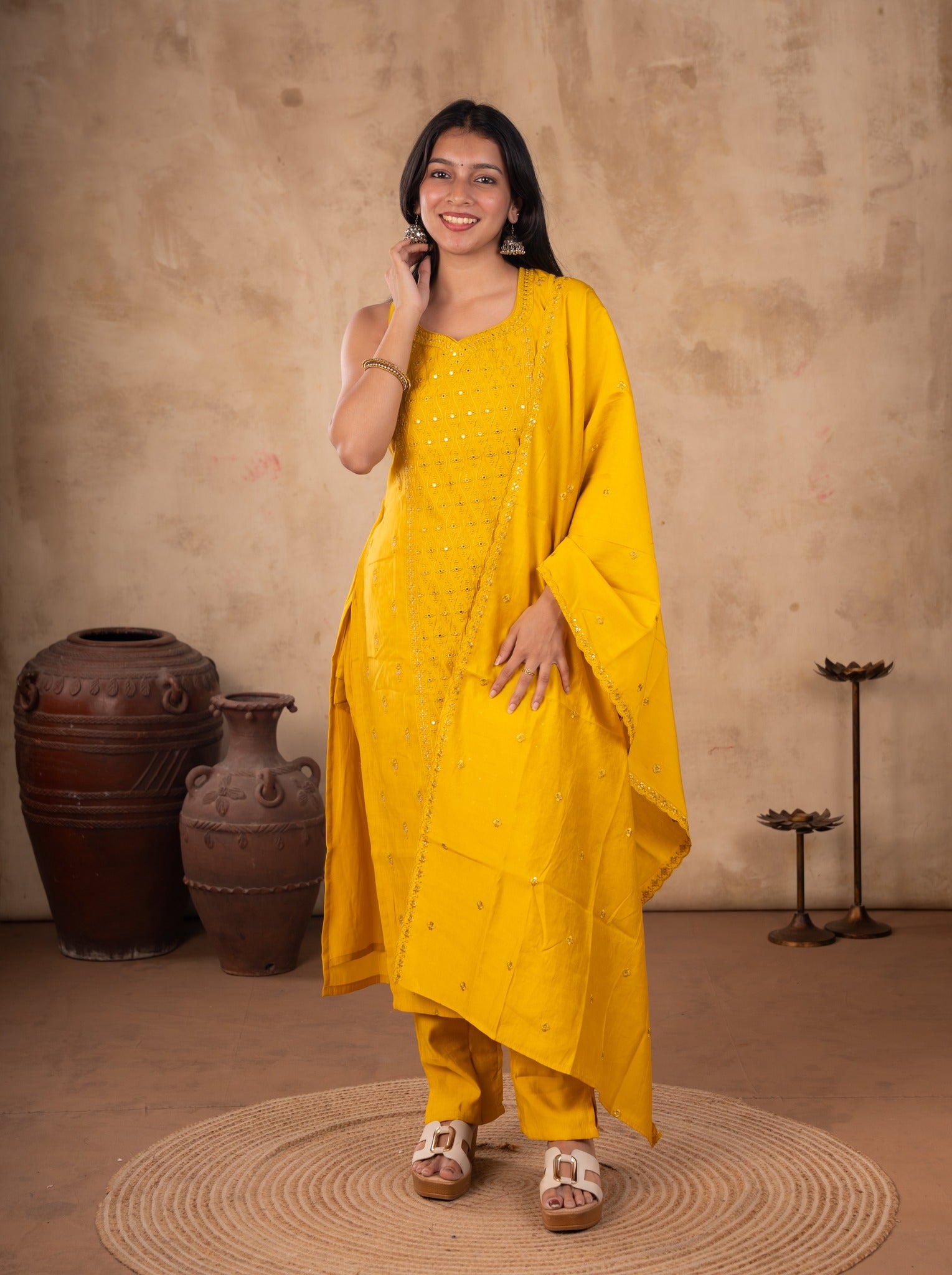 Front view of a model in a yellow cotton salwar suit with a sleeveless sequinned kurta, matching pants and a dupatta over one shoulder