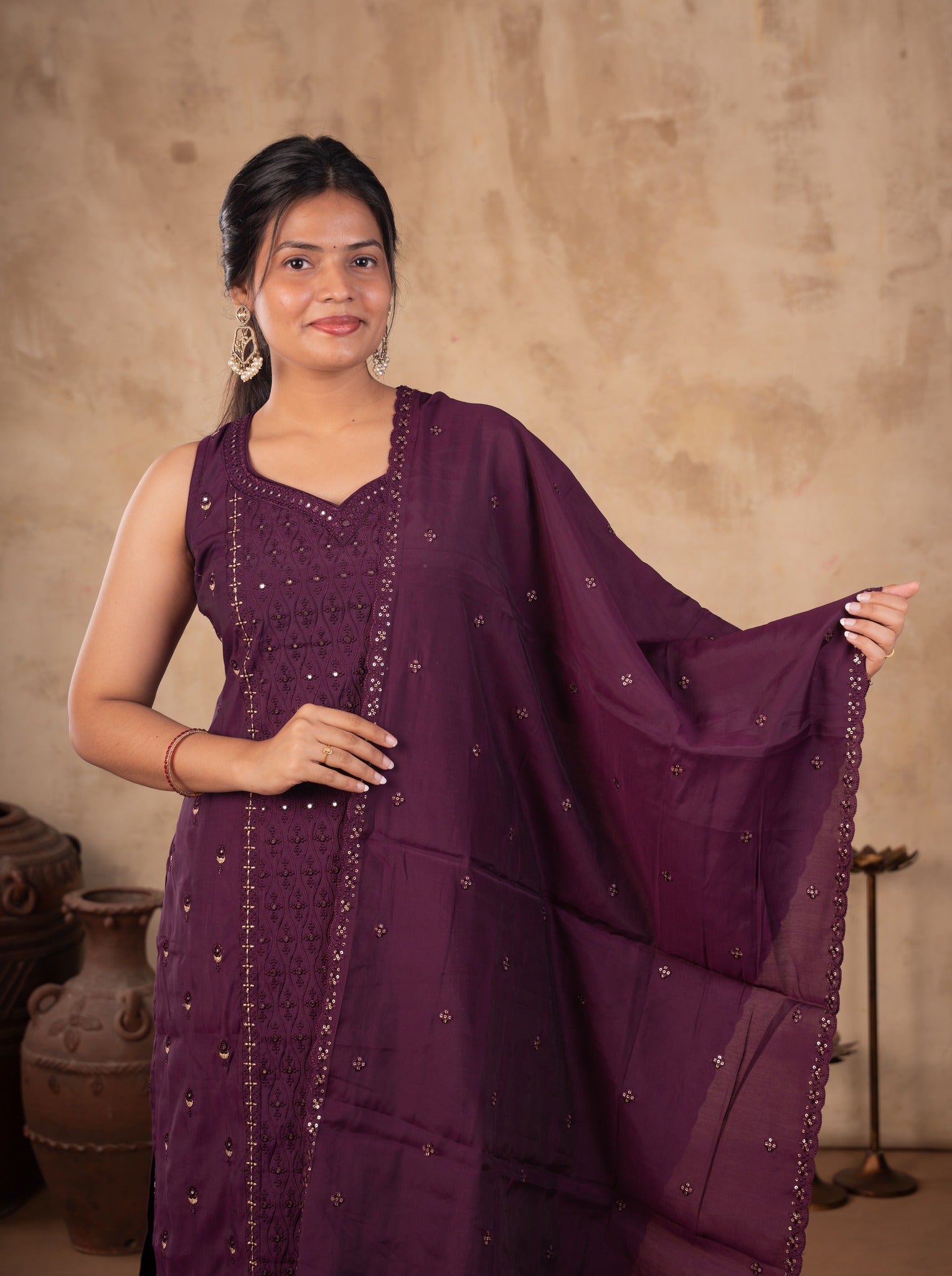 Model holding the dupatta of a purple cotton salwar suit with delicate motifs and decorative trim