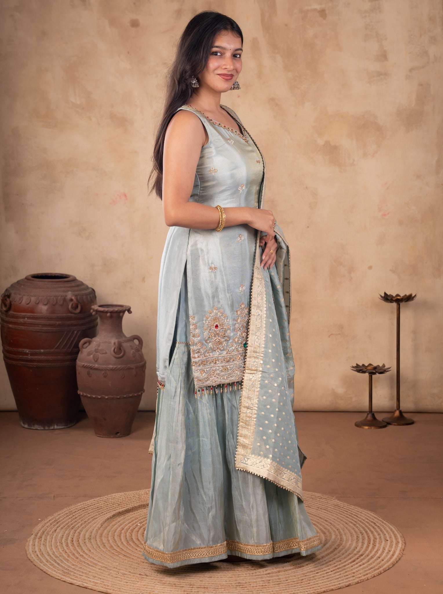 Full-length view of a sea green silk salwar suit showing the embroidered kurta hem and flared trousers