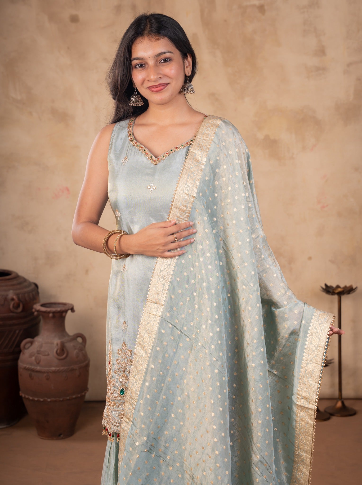 Half-length view of a sea green silk kurta with the gold-bordered dotted dupatta held out