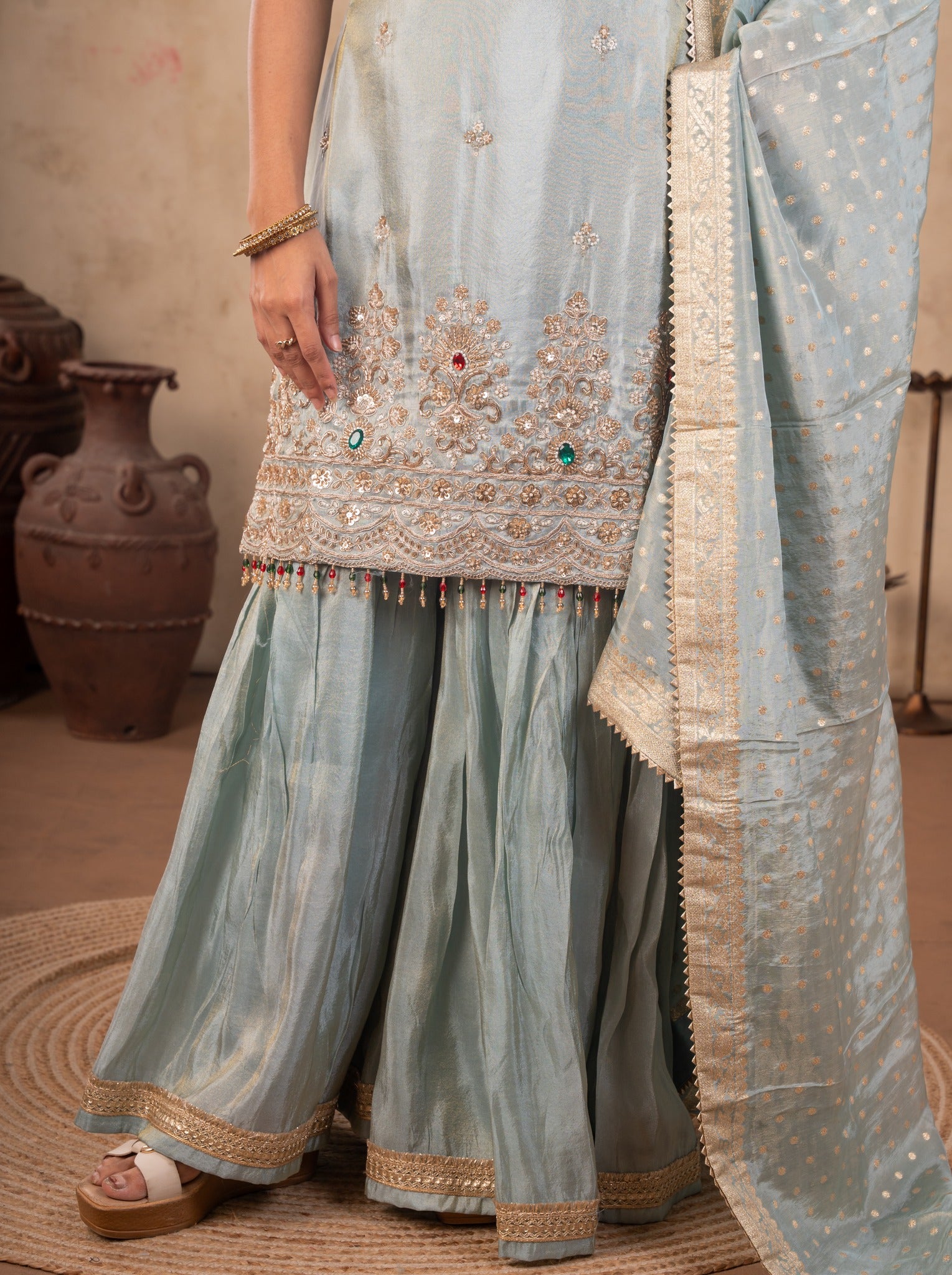 Detail of the flared trousers, embroidered kurta hem and gold-bordered dupatta of the sea green suit