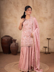 Front view of a model in a peach silk salwar suit with an embroidered kurta, flared sharara trousers and a dotted dupatta