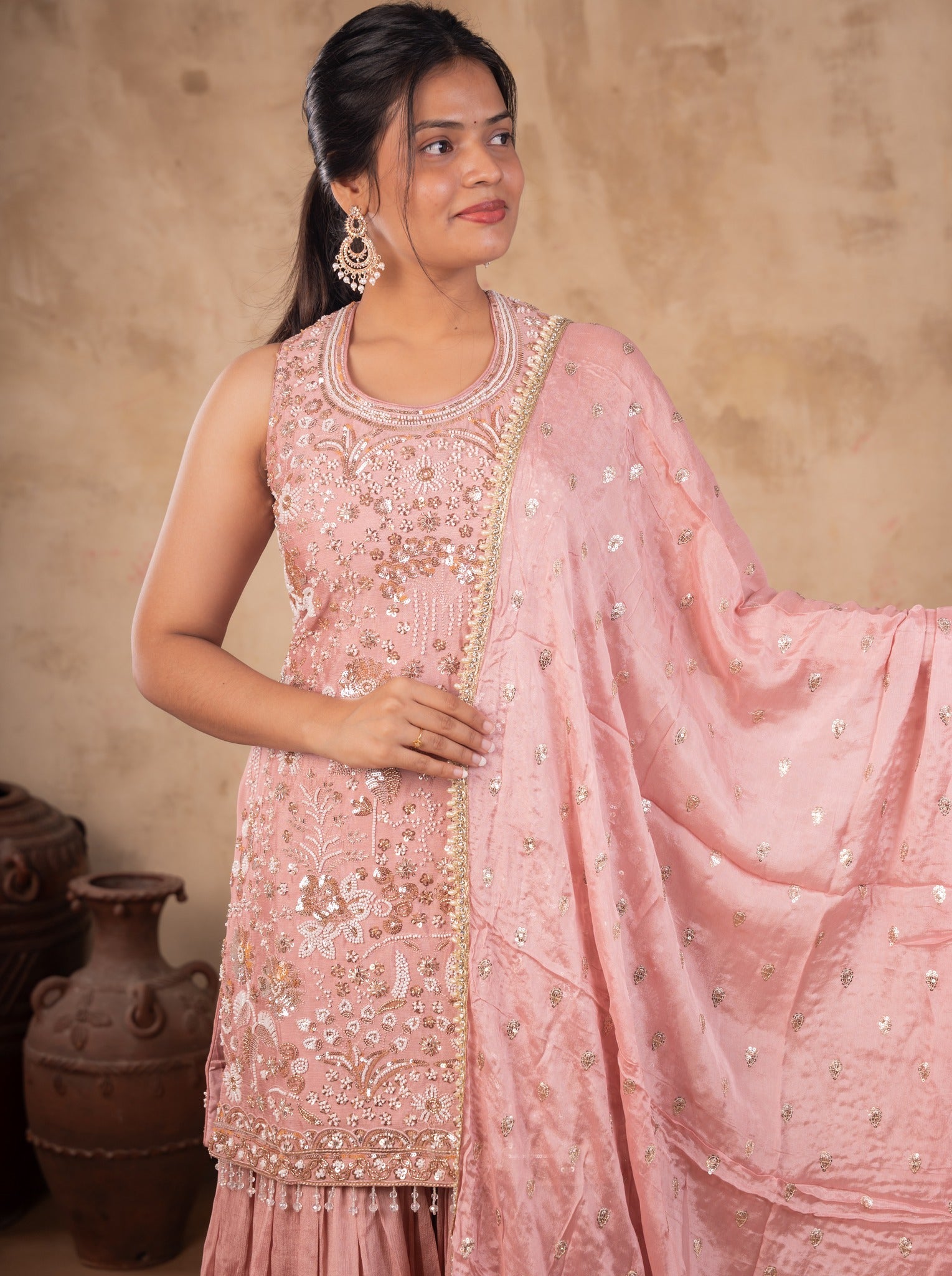 Model holding the dupatta out to the side, showing the embroidered peach silk kurta