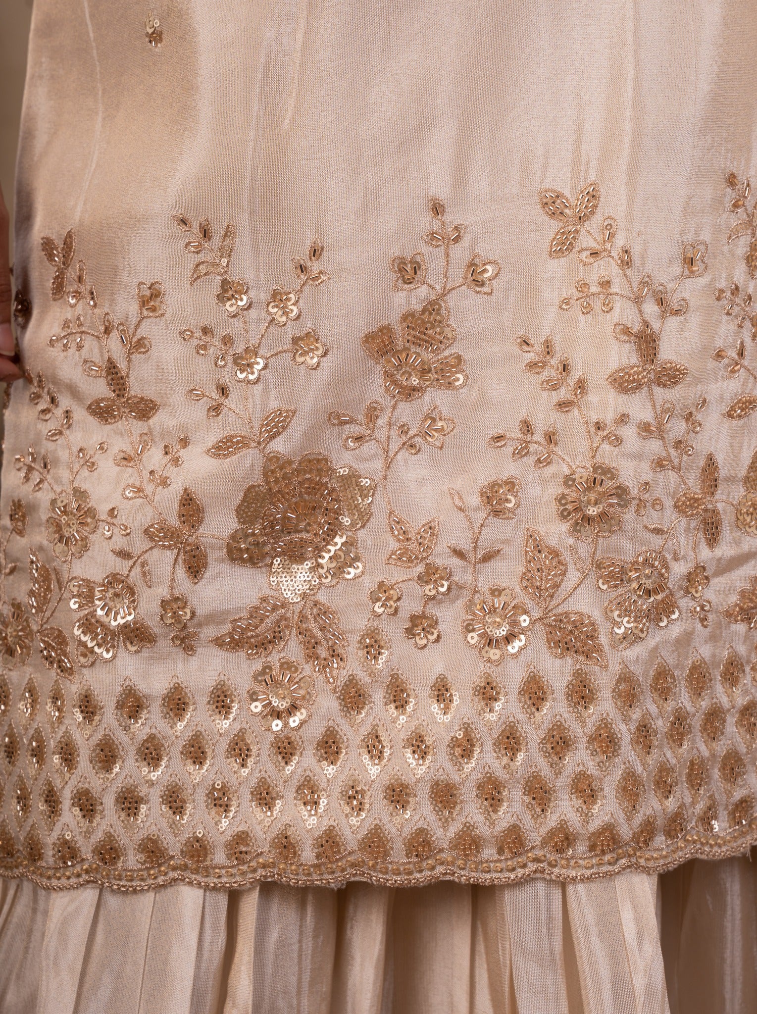 Detail of the floral sequin embroidery along the hem of the white silk kurta