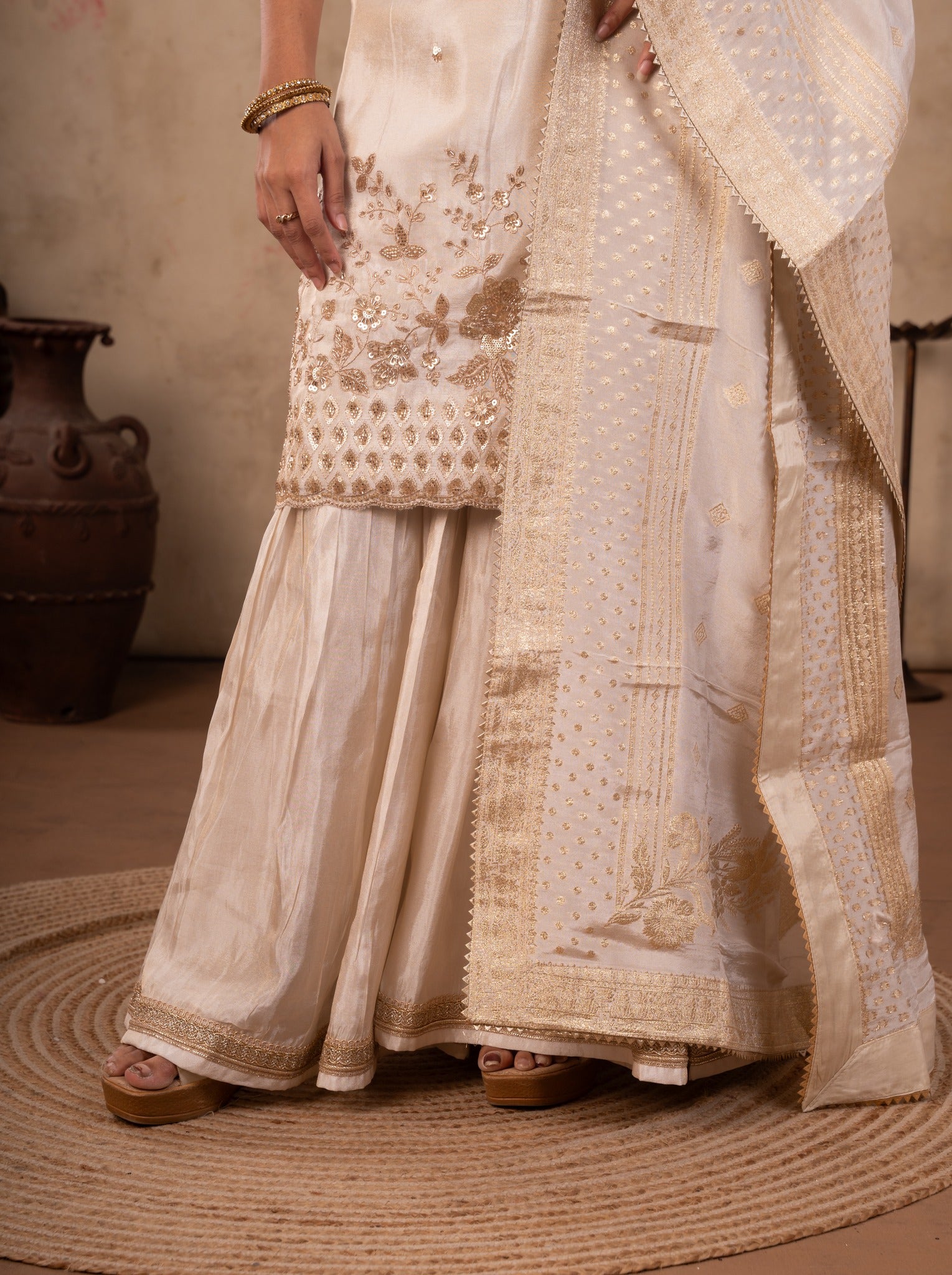 Detail of the flared white silk trousers and the embroidered kurta hem