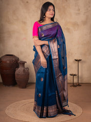 Front view of a blue Banarasi silk saree with an ornate broad border and pallu, paired with a bright pink blouse