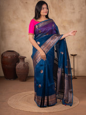 Model holding the pallu of a blue Banarasi silk saree with metallic woven motifs