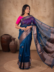 Model holding out the ornate pallu of a blue Banarasi silk saree with a pink blouse