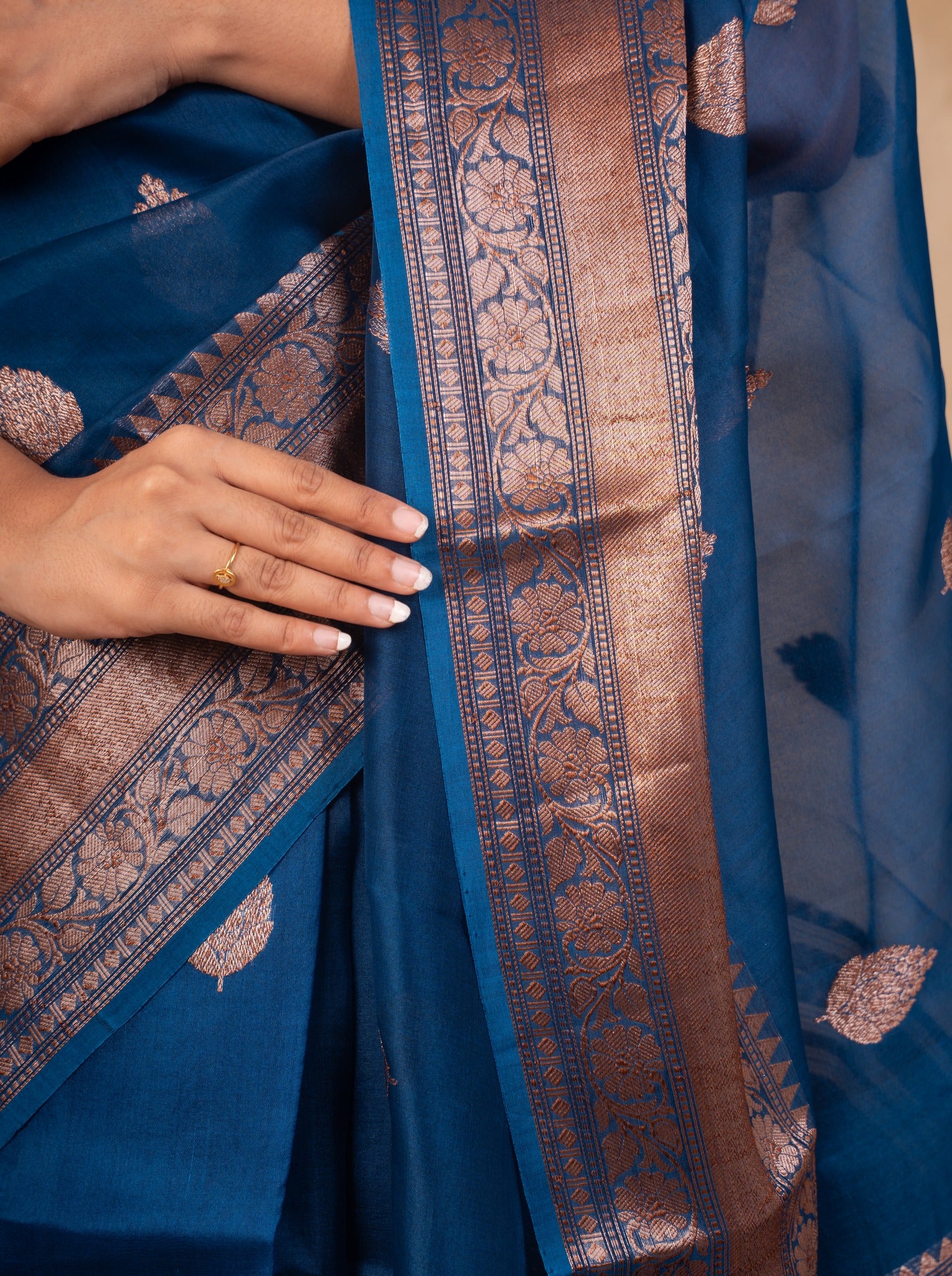 Detail of the ornate woven metallic border and leaf motifs on the blue Banarasi silk saree