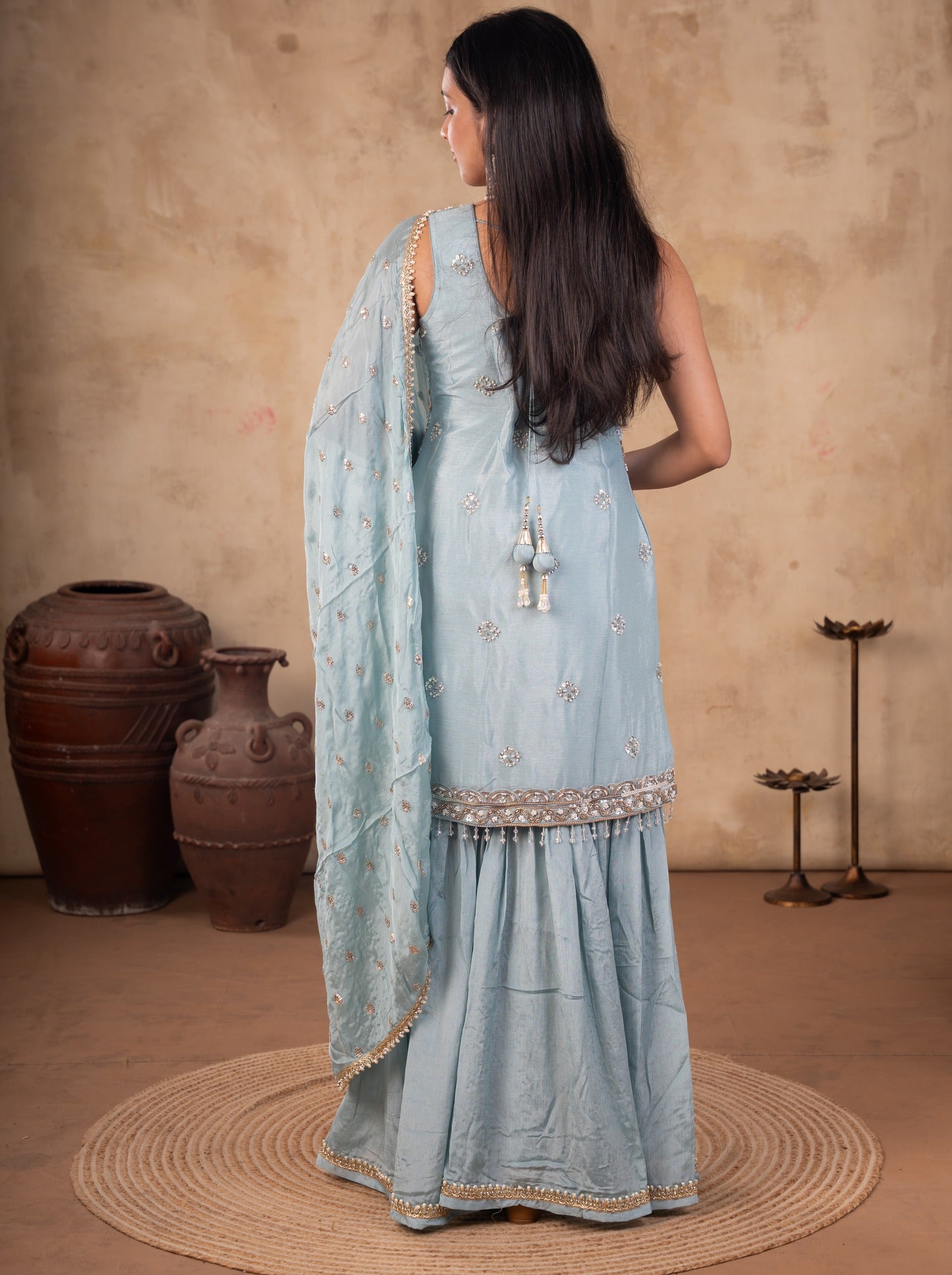 Back view of a sage green georgette sharara suit with the dupatta draped across the back