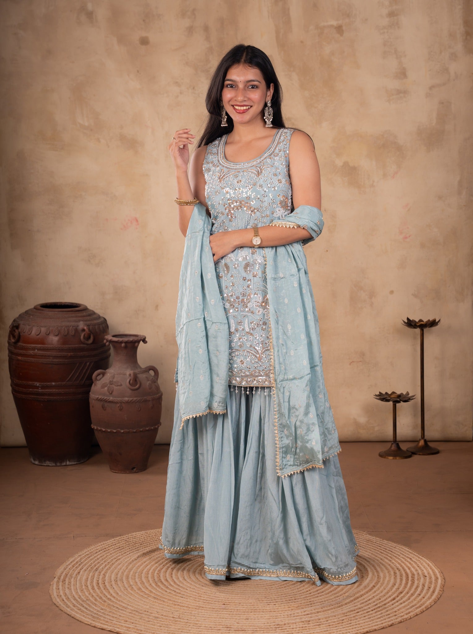 Full-length view of a sage green georgette sharara suit with the dupatta draped over both shoulders