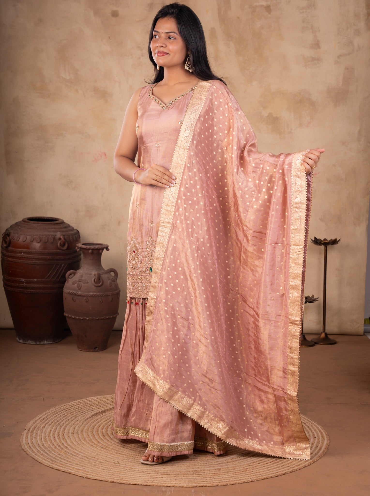 Model holding out the dotted blush pink dupatta over a georgette sharara suit