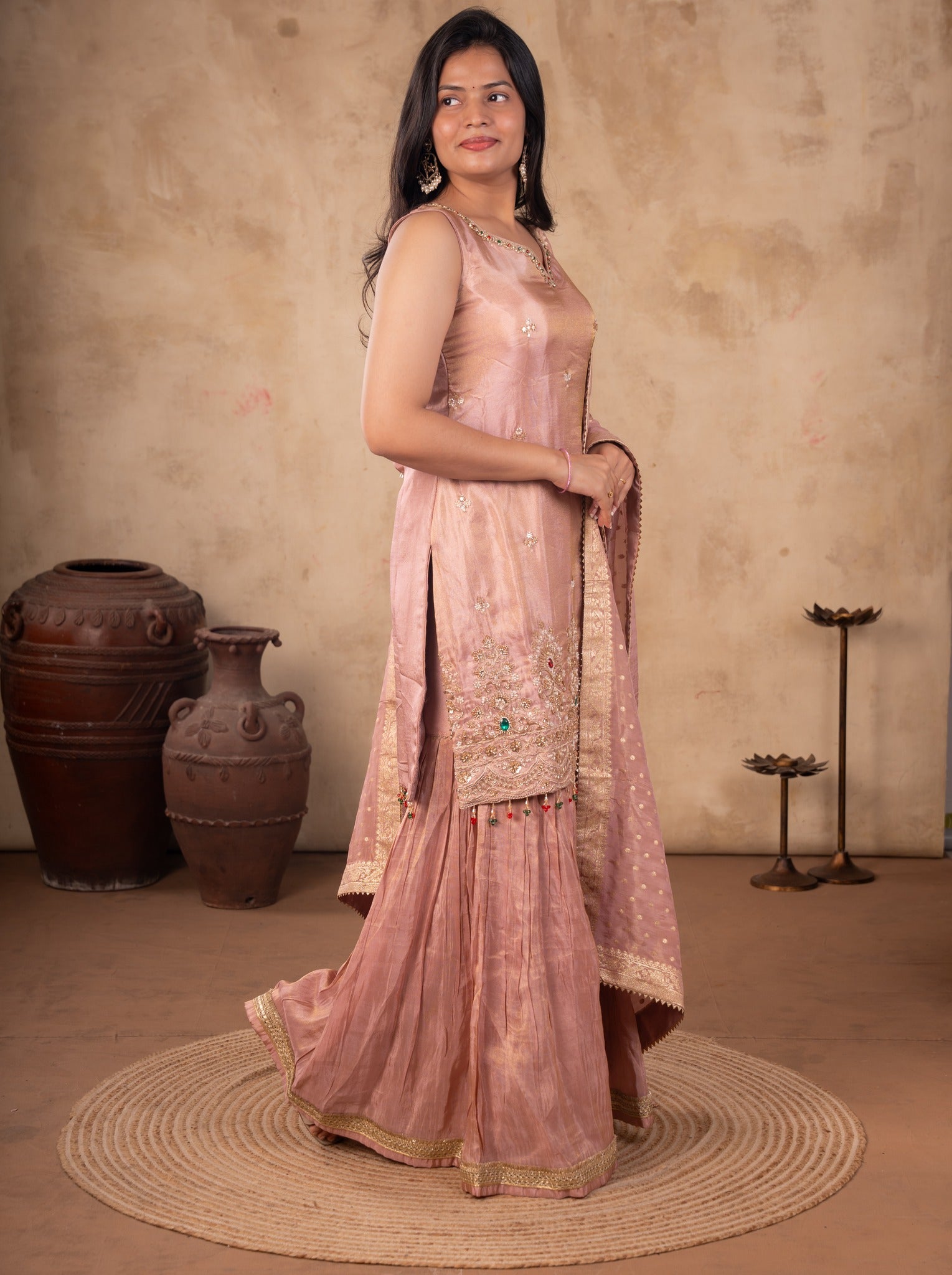 Model in a blush pink georgette sharara suit with the flared sharara and draped dupatta