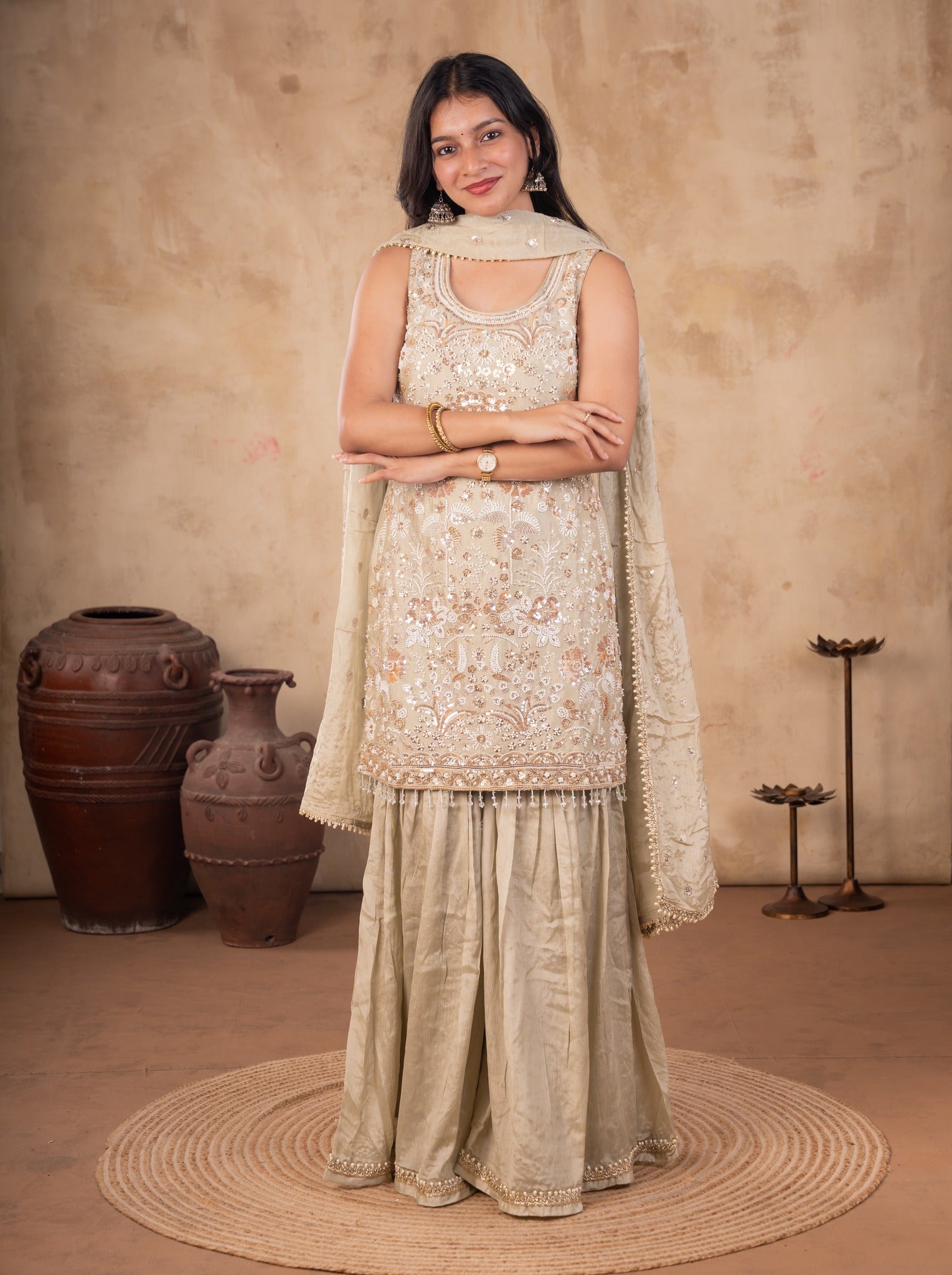 Full-length view of a light olive green sharara suit with an embroidered sleeveless kurta and dupatta