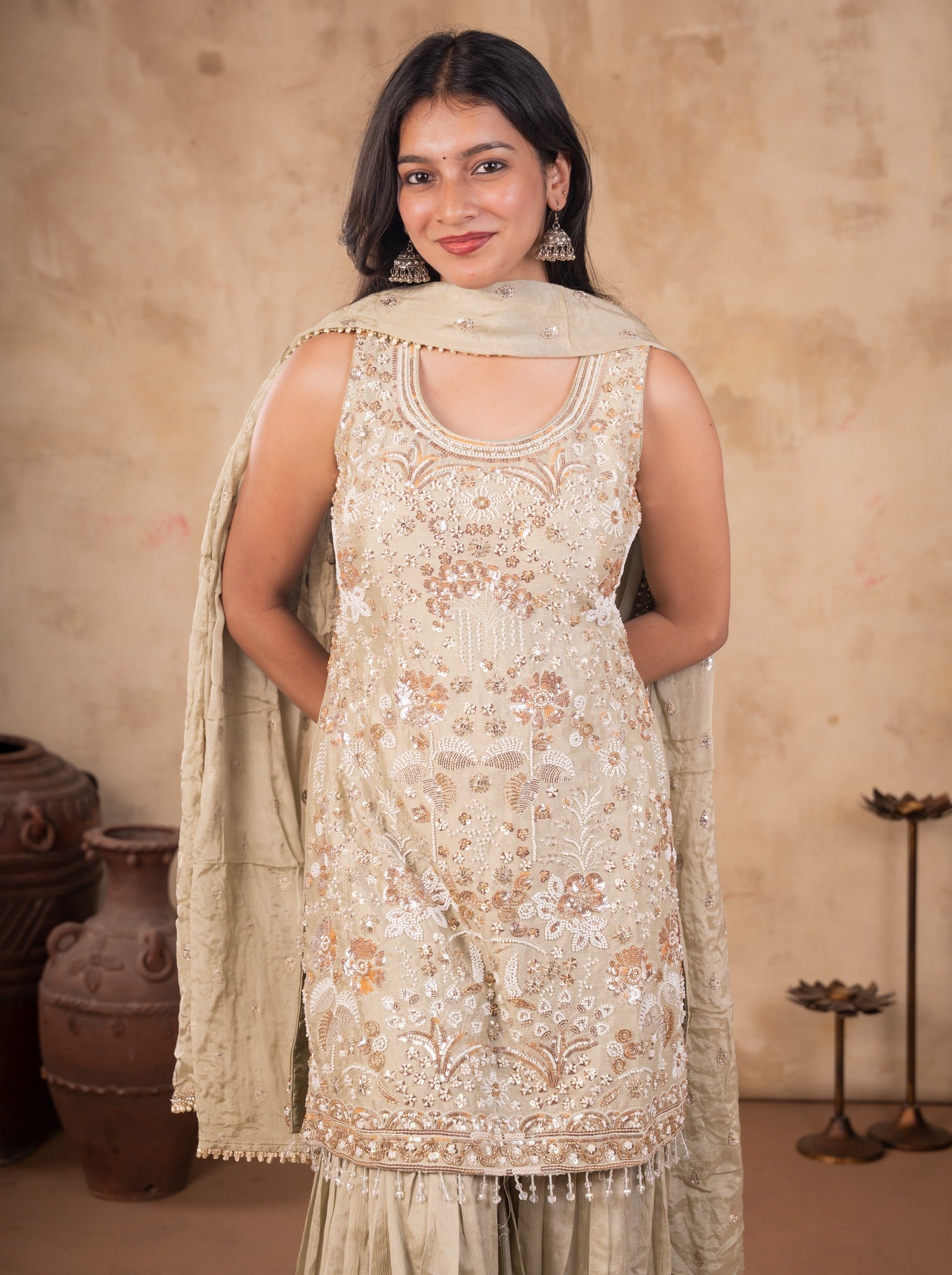 Model smiling in a light olive green georgette kurta with floral embellishments and a dupatta