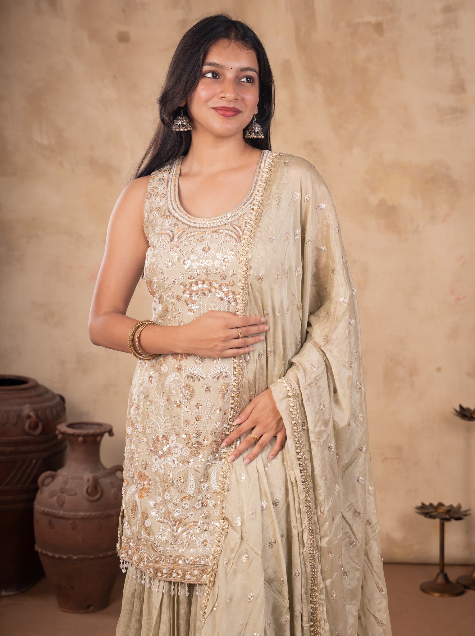 Model in a light olive green sharara suit with the dupatta's decorative trim visible