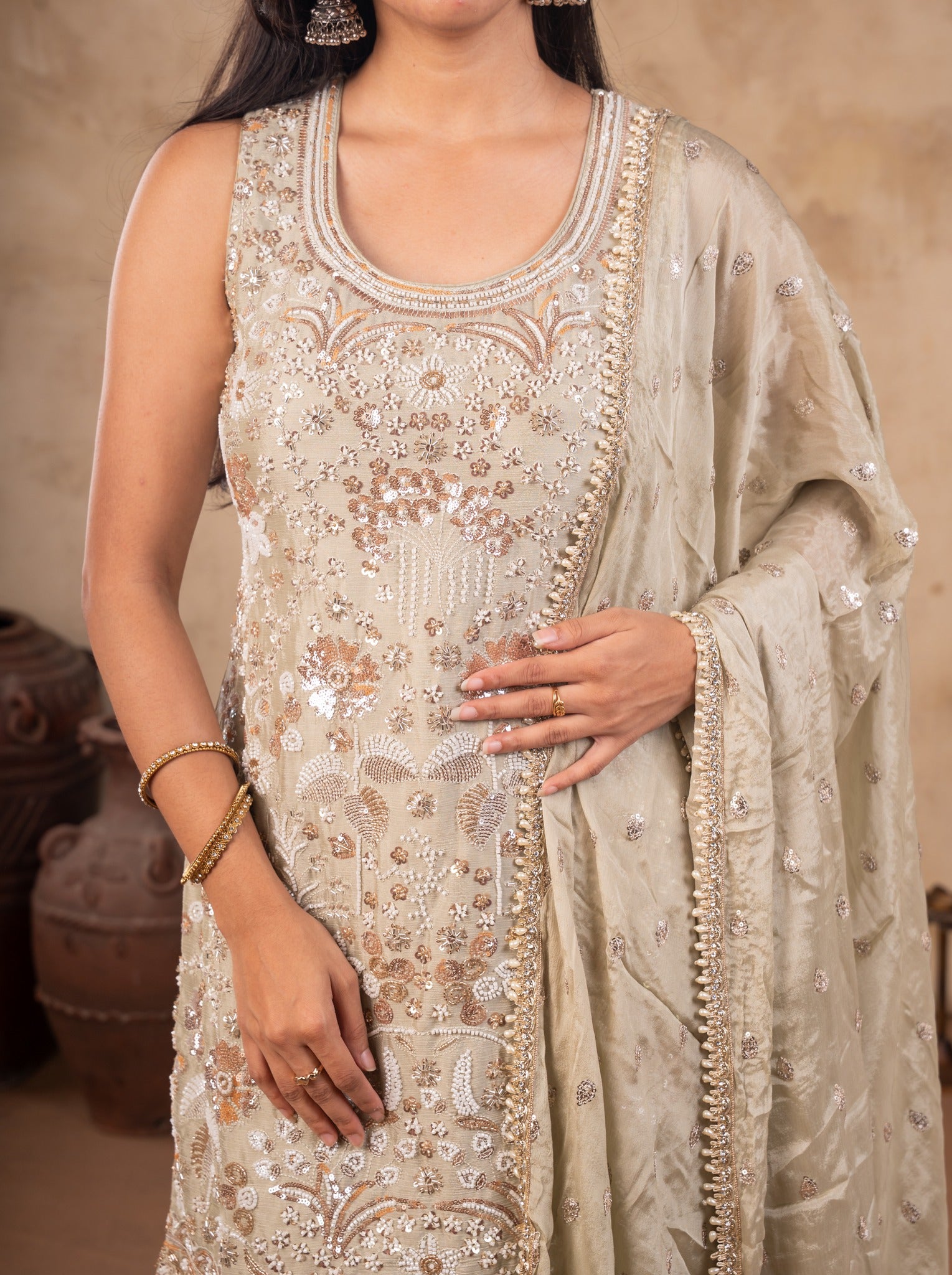 Close-up of the floral sequin embroidery and embellished neckline on a light olive green kurta