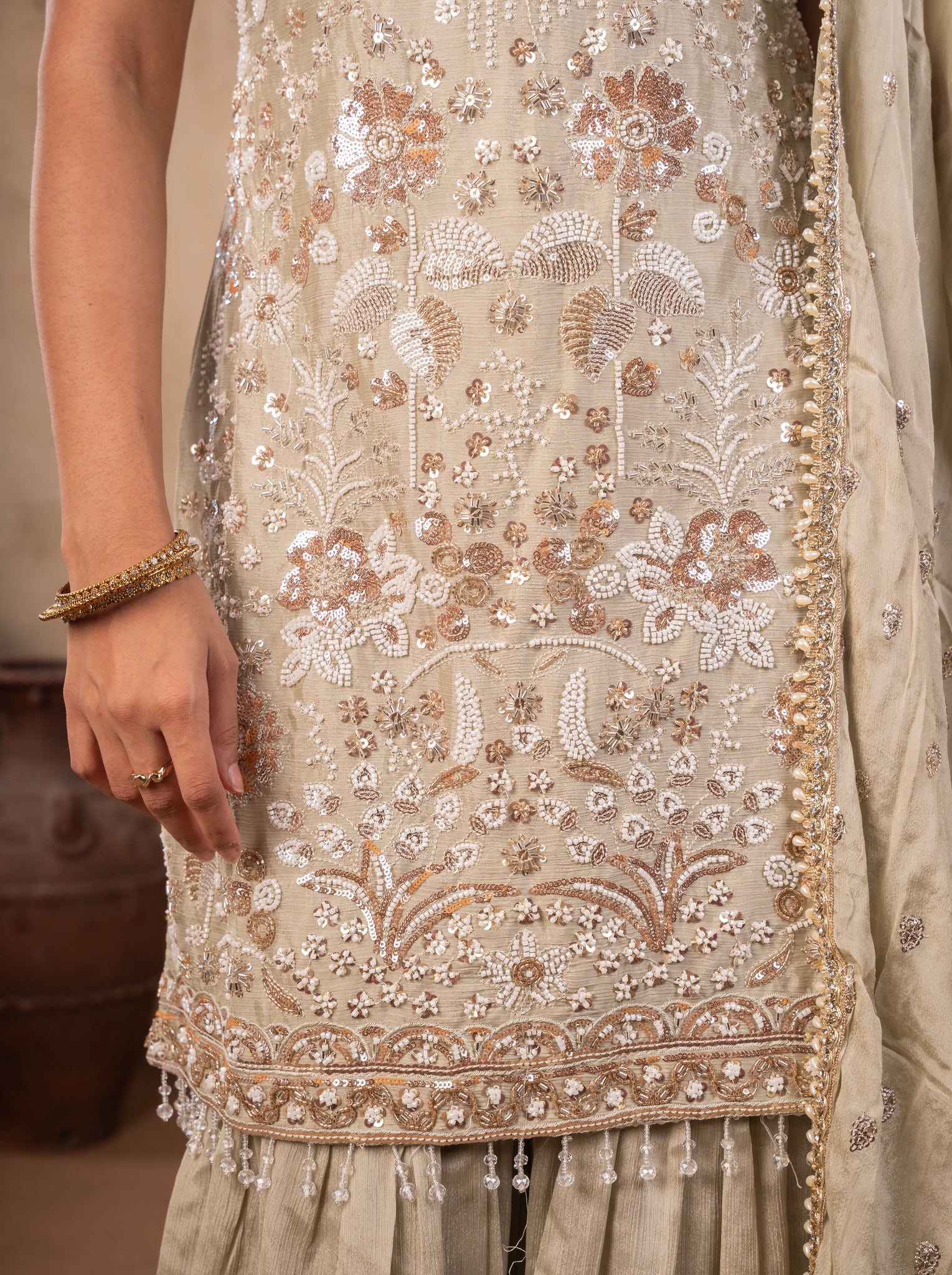 Detail of the sequin and thread embroidery with beaded hem on the light olive green kurta