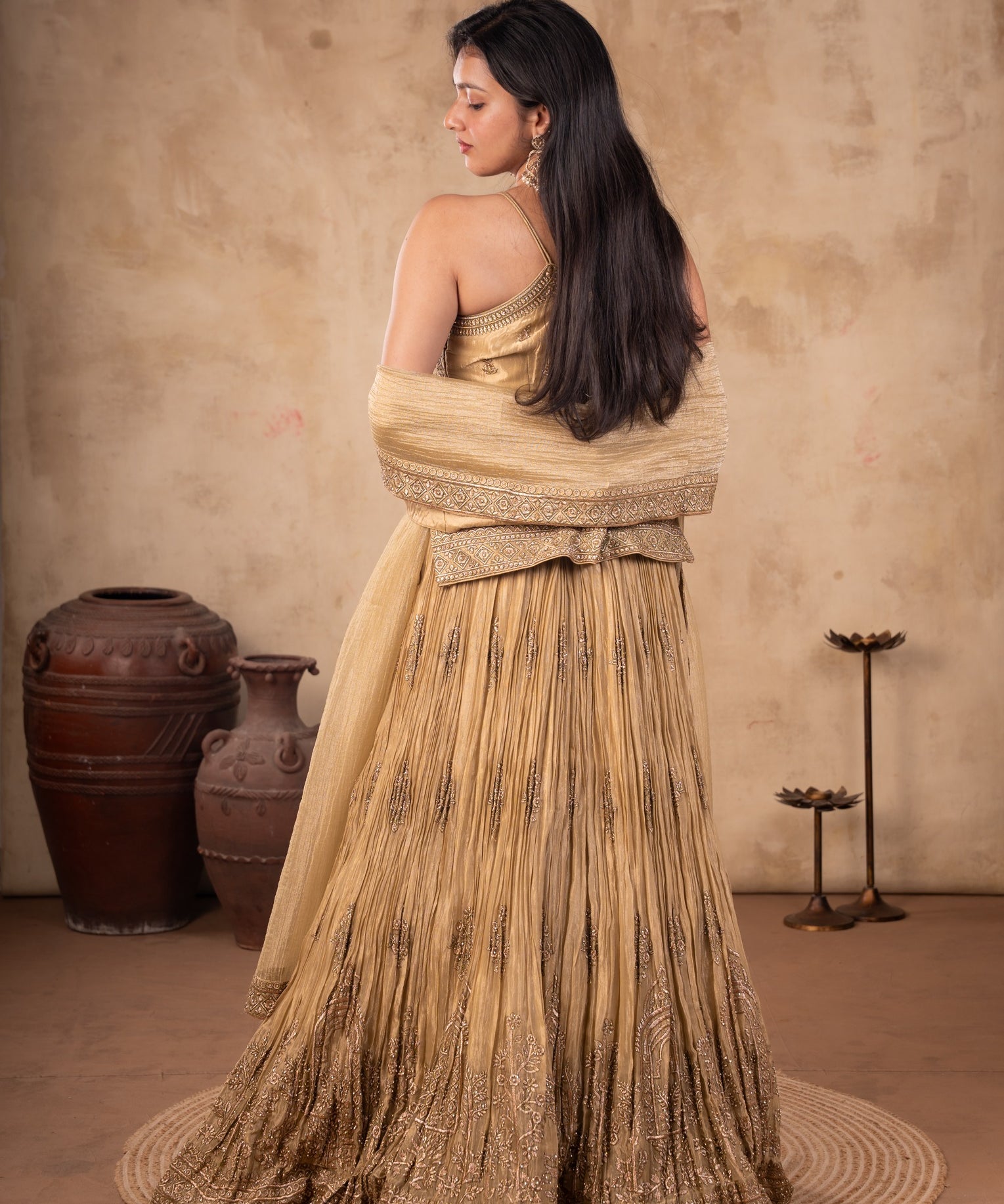 Model wearing a pista organza lehenga with a pleated, embroidered skirt, a matching strappy choli, and a sheer dupatta with an ornate border.
