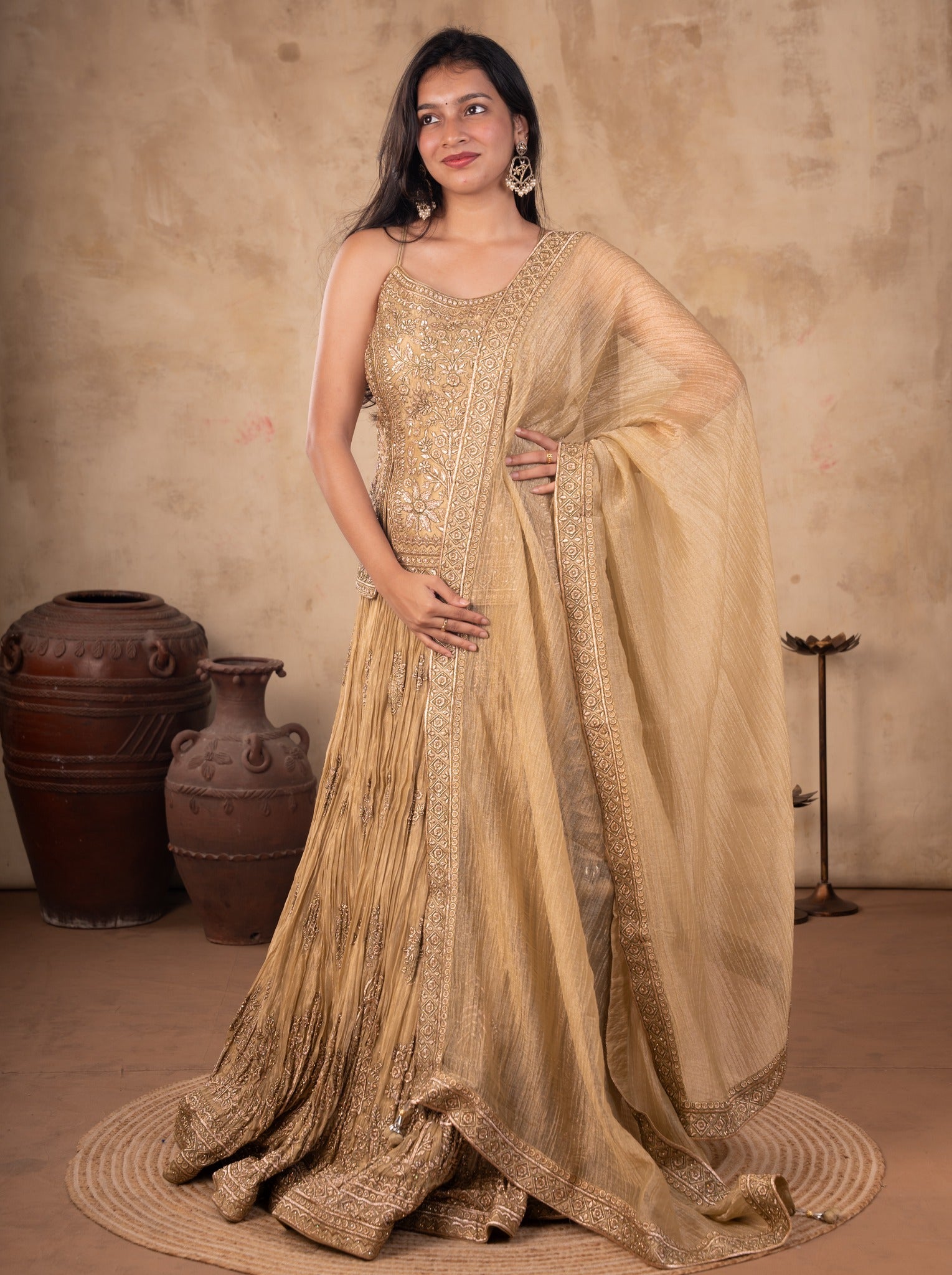 Front view of a model in a pista organza lehenga with a pleated embroidered skirt, strappy choli and sheer dupatta