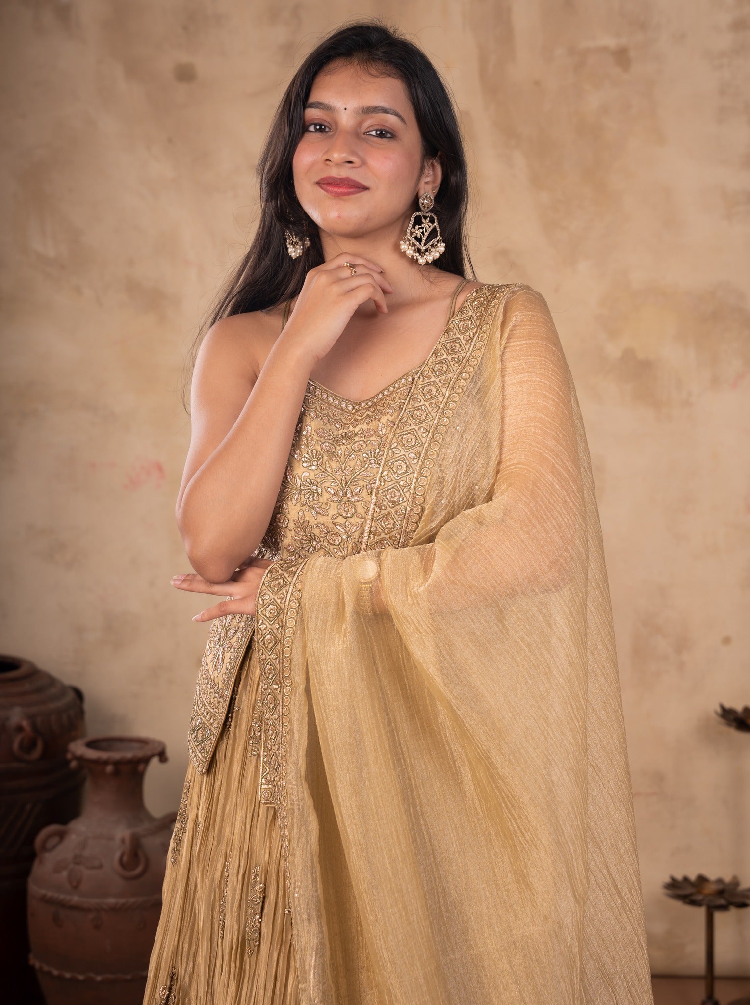 Model touching her chin in a pista organza lehenga with an embroidered strappy choli and draped dupatta