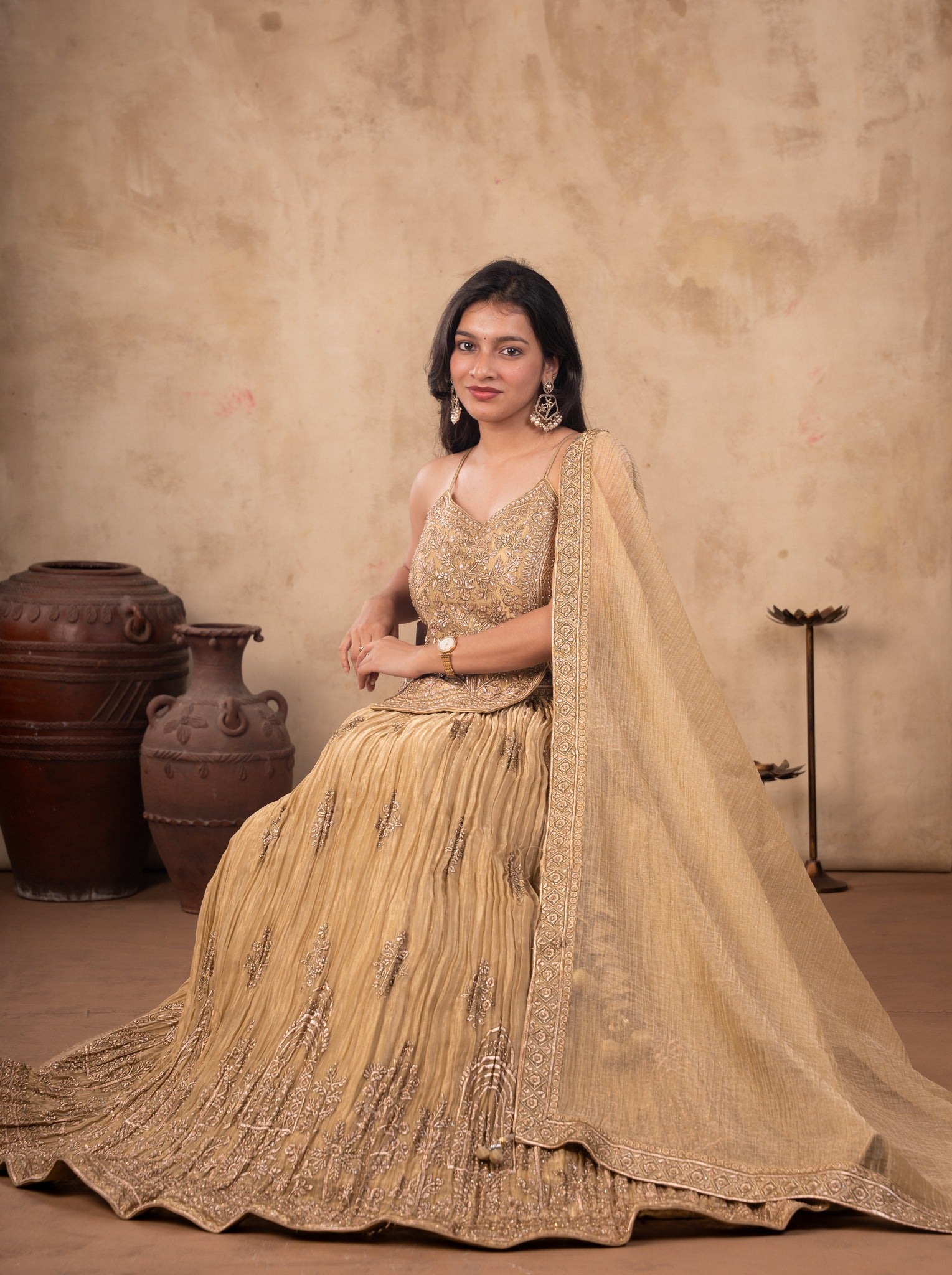 Model seated in a pista organza lehenga with the pleated skirt spread around her