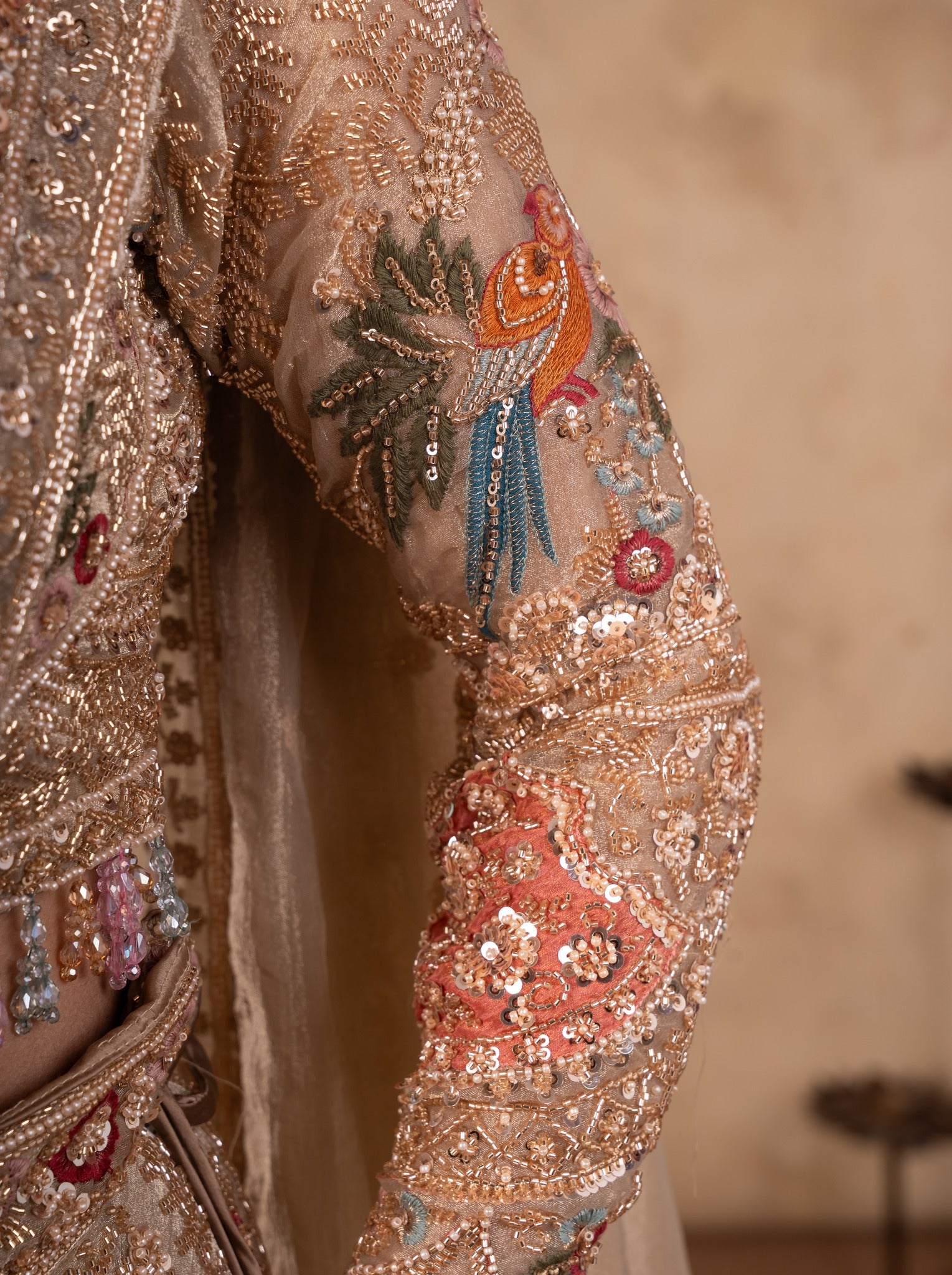 Detail of the colourful bird embroidery on the sleeve of the pista organza lehenga blouse