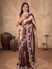 Front view of a model in a lustrous bronze-toned saree with a deep purple border and ornate gold embellishments