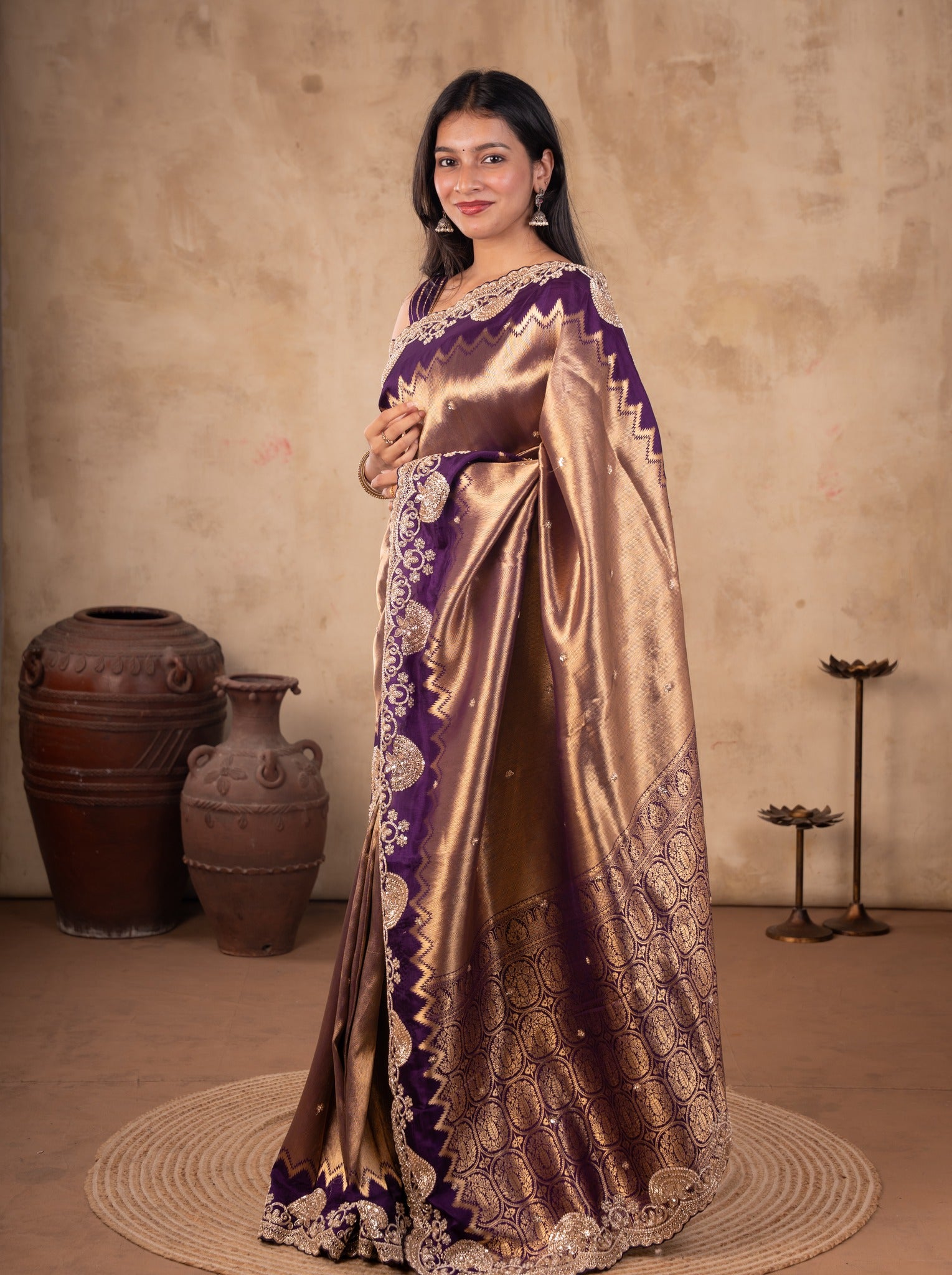Full-length view of a bronze-toned saree with a deep purple embellished border and patterned pallu