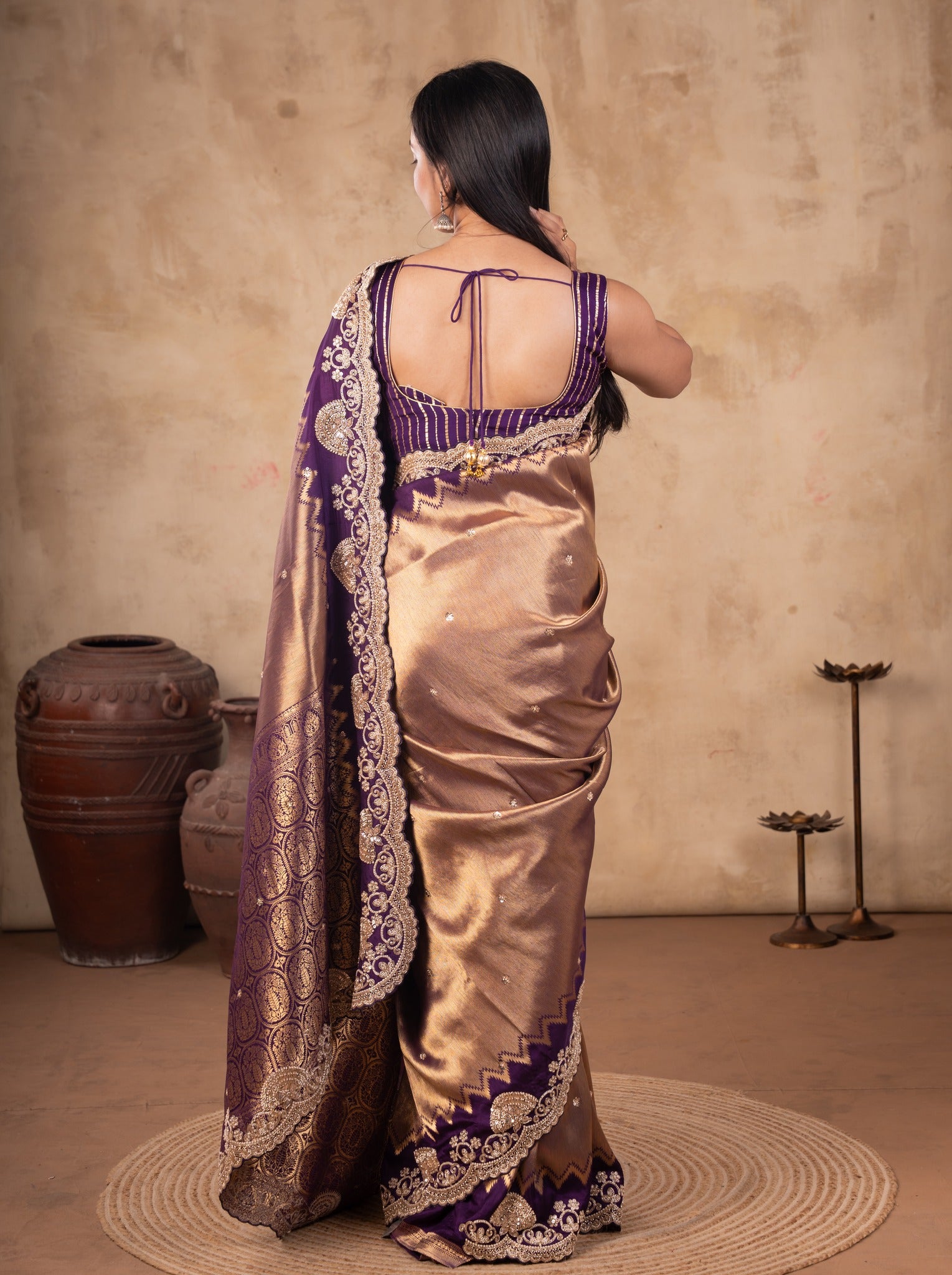 Back view of a bronze-toned saree showing the purple blouse back and embroidered pallu border