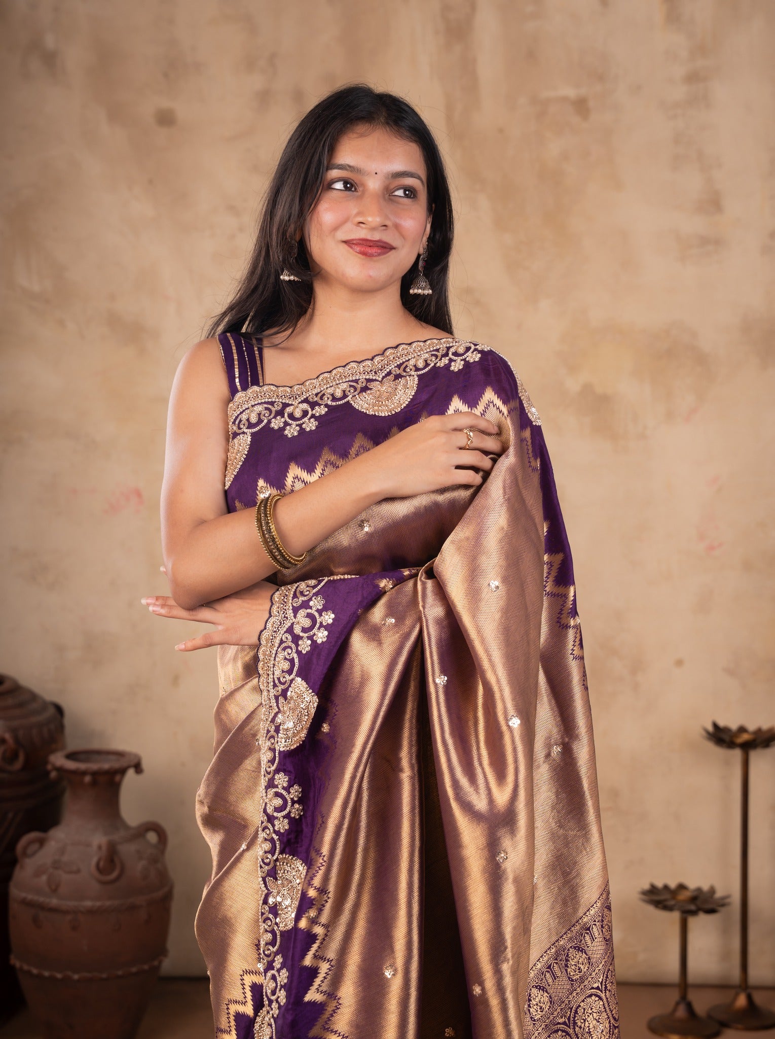 Half-length view of a bronze-toned saree with gold floral and paisley embellishments on the purple border