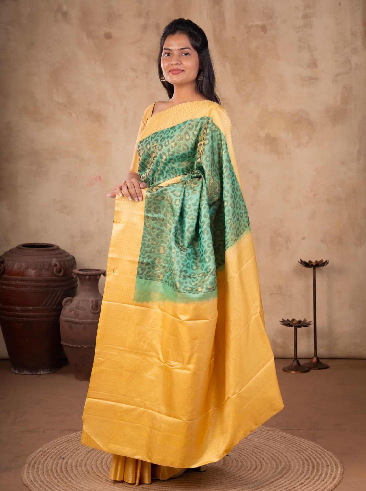 Model wearing a sea green soft silk saree with an all-over patterned design, wide golden-yellow border and pallu, and matching yellow blouse.