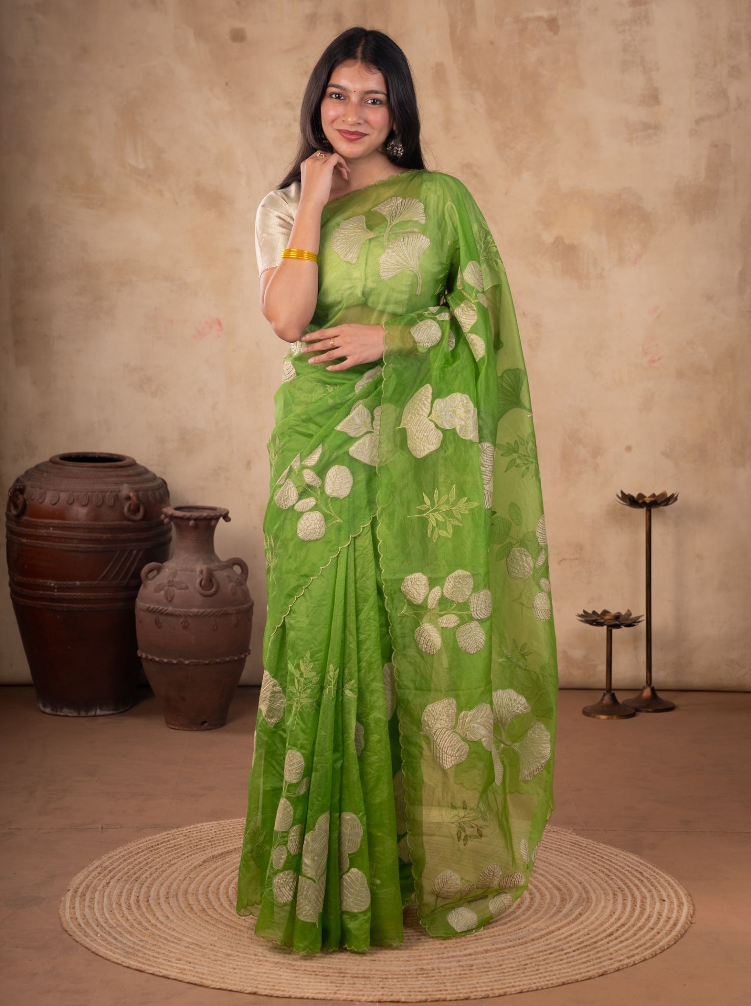 Model wearing a green crepe saree with large cream floral motifs, a delicate scalloped border, and a cream short-sleeved blouse